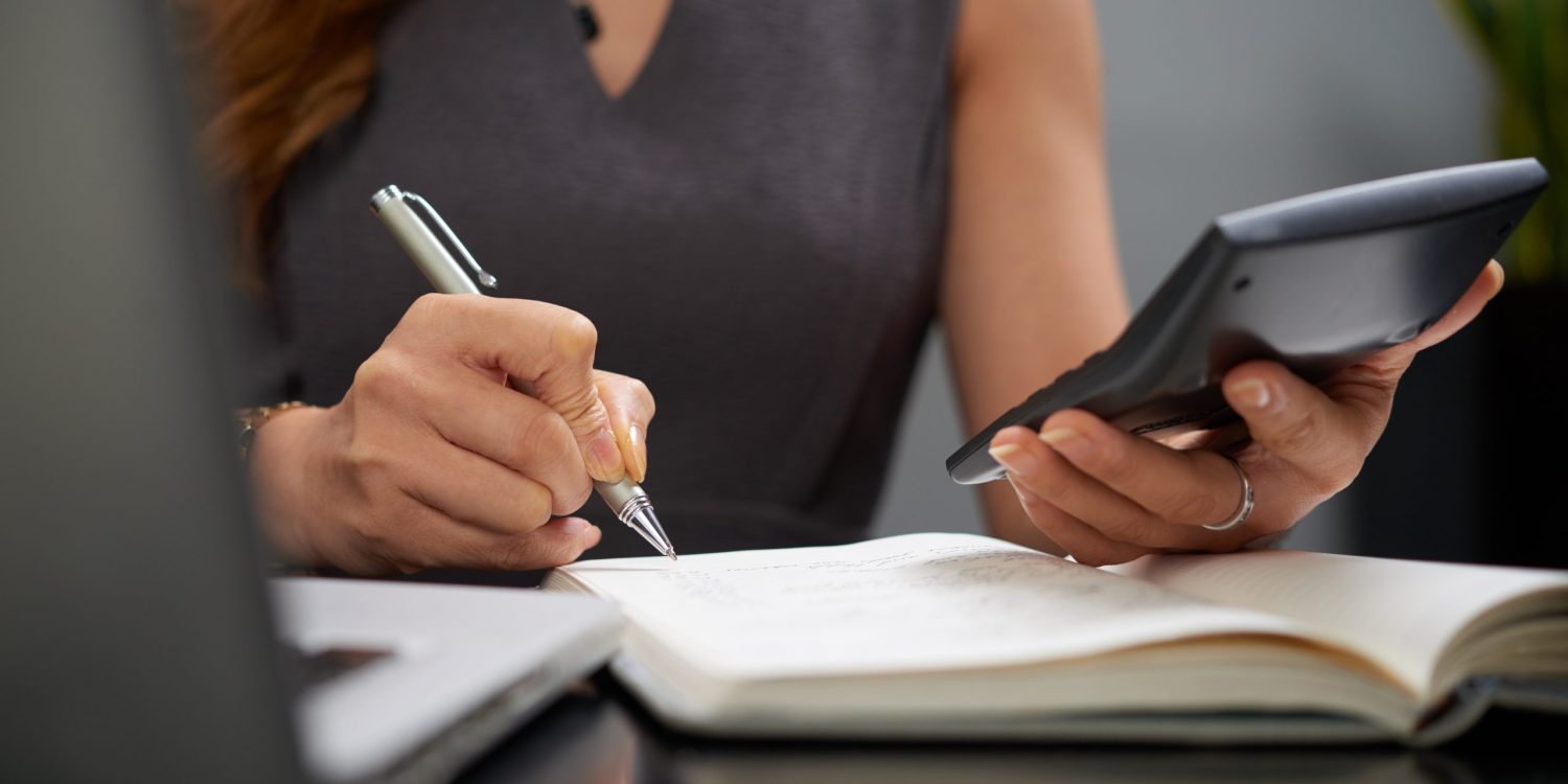 Close-up image of business lady making calculations and taking notes